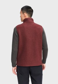 Rød fleecevest med høj krave, kontrasterende grå strikkede ærmer og en glat tekstur. Har et rent, minimalistisk design uden synlige logoer.