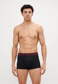 Schwarze Herrenboxershorts aus Baumwolle mit einem roten, gebrandeten Bund. Merkmale ein enganliegendes Design und eine glatte Textur.