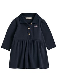 Námořnické modré šaty s dlouhými rukávy, polo límečkem, zapínáním na knoflíky, nařasenou sukní a vyšívaným logem na hrudi. Měkký bavlněný materiál.