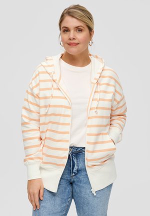 Striped zip-up hoodie in light peach and white, featuring a cozy hood, front pockets, and ribbed cuffs; worn over a plain white tee.