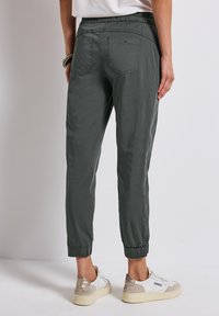 Grå joggerbyxor med elastisk midja och smalnande muddar, bakfickor och ett lätt tyg. Matchade med vita och beige sneakers.