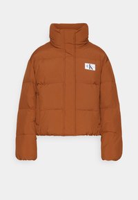 Veste matelassée marron avec col montant et écusson logo sur la poitrine gauche, présentée sur fond blanc uni.