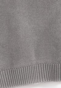 Maglione grigio lavorato a maglia con un motivo testurizzato. Presenta un orlo e polsini a costine, realizzato in un tessuto morbido e liscio.