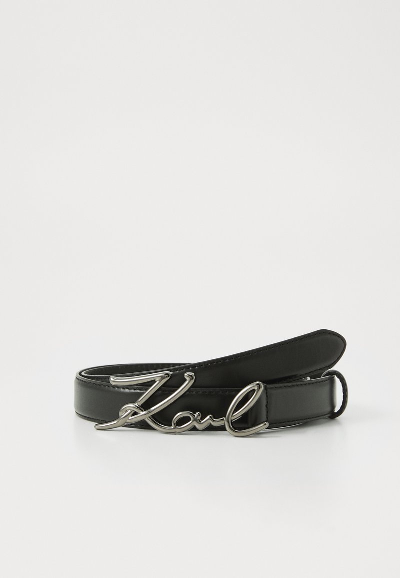 Zwarte leren riem met een glanzende zilveren metalen gesp in de vorm van de naam "Karl." Zachte textuur met een minimalistisch ontwerp.