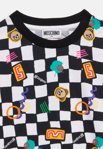 Ύφασμα ασπρόμαυρο καρό με πολύχρωμες καρτούν αρκούδες, αριθμούς, αφηρημένα σχήματα και κείμενο "Moschino" κοντά στην μαύρη ετικέτα γιακά.
