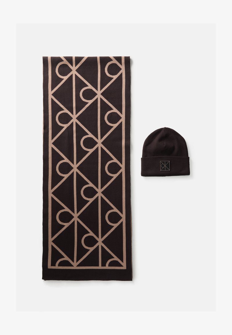 Black and beige scarf with geometric pattern next to matching black beanie hat with a square embroidered logo patch.