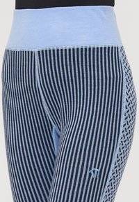 Blå och marinblå leggings med vertikala ränder och en mönstrad sidpanel. Har en ljusblå midjeband och dekorativ sömnad.