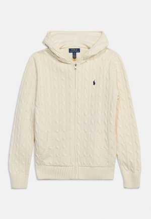 Kermanvärinen kaapelikuvioitu vetoketjuhuppari, jossa etutaskut ja pieni tummansininen Polo Ralph Lauren -logo rinnassa.