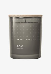 Gray glass candle container with wooden lid, featuring intricate patterned engraving and white text stating "SKANDINAVISK RO Tranquility."