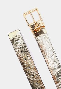 Guld metallisk faux læderbælte med en tekstureret overflade, featuring en guldspænde og et logo-akkcent. Fem justerbare huller til tilpasning.