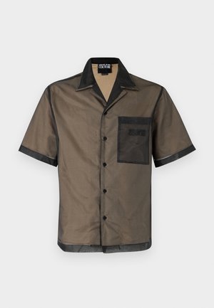 Ruda permatoma trumpomis rankovėmis užsegama palaidinė su juodu apykakle, kišene ir apvadais, su „Versace Jeans Couture“ ženklu ant kišenės.