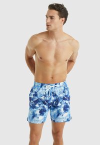 Zwemshorts in een blauw-witte tie-dye patroon, gemaakt van lichtgewicht stof. Voorzien van een elastische tailleband met een trekkoord en zijzakken.
