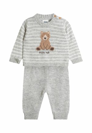 Grey knitted baby outfit with a striped sweater featuring a bear graphic and text "little cub." Bottoms are solid grey with ribbed cuffs.