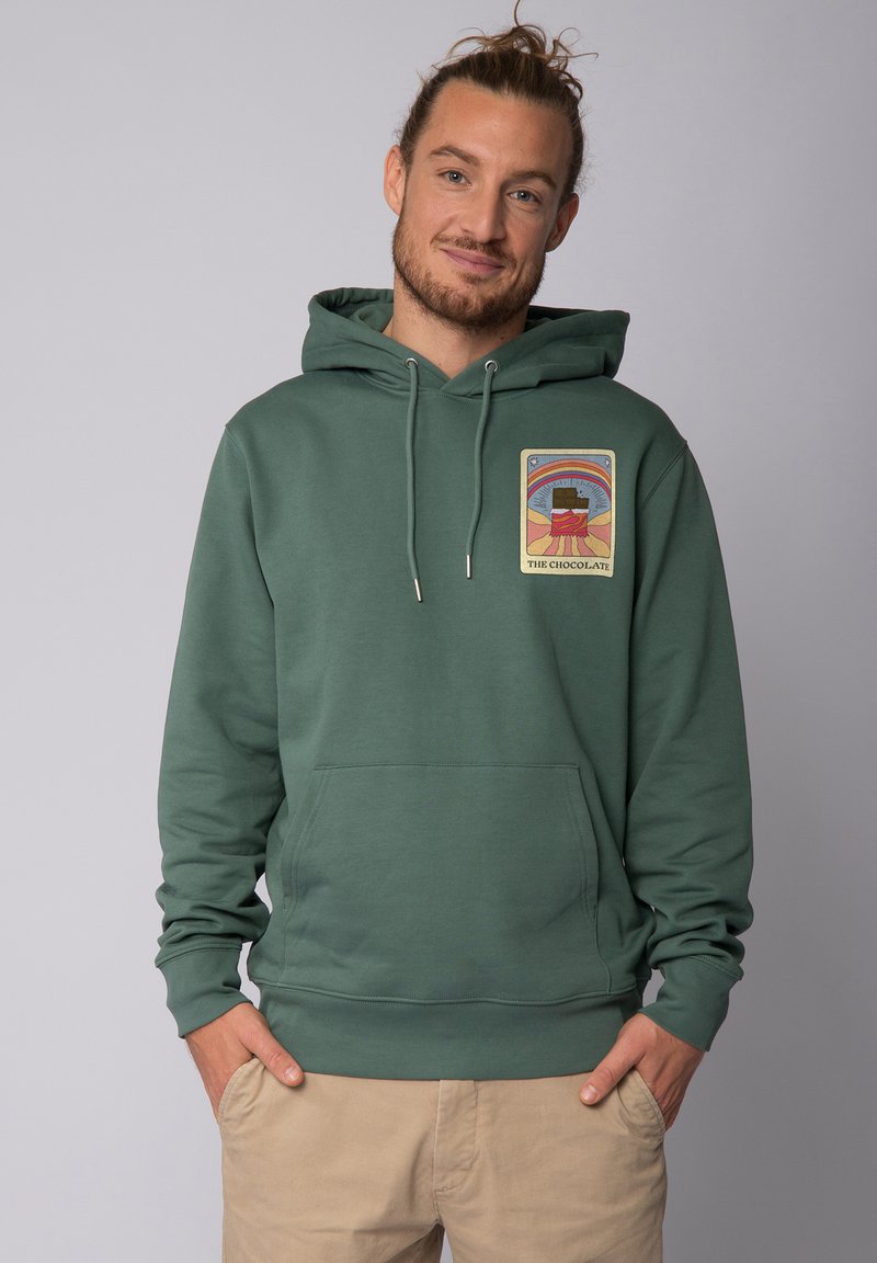 Hoodie en coton vert avec une poche kangourou à l'avant et des cordons de serrage. Présente un patch graphique coloré sur la poitrine gauche représentant du chocolat.