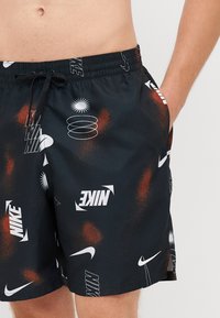 Čierne plavky s farebným grafickým vzorom, obsahujúcim logá Nike, abstraktné tvary a elastický pás na šnúrku.