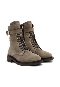 Bottines en daim gris avec un bout rond, un laçage à l'avant et une fermeture éclair sur le côté. Elles disposent d'une sangle décorative et d'un talon épais.