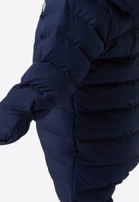 Marineblå dunjakke med quiltet design, utstyrt med hette og elastiske mansjetter. Stoffet virker glatt og vannavstøtende.