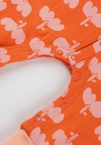 Oranger Baumwoll-Body mit einem rosa Blumenmuster, Druckknopfverschlüsse am Ausschnitt und kontrastierenden rosa Bündchen. Glatte Textur.