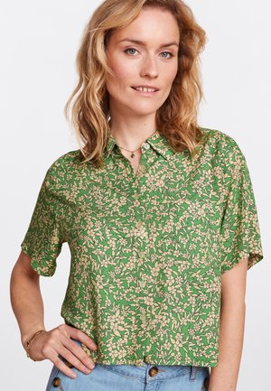 Blusa verde a maniche corte con motivo floreale beige, caratterizzata da una chiusura frontale con bottoni e una vestibilità rilassata. Tessuto morbido con una texture leggera.