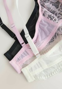 Tri čipkaste nedrčke v črni, roza in beli barvi, prikazane zložene z nastavljivimi naramnicami in nežnimi cvetličnimi vzorci.