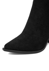 Czarne botki z sztucznego zamszu za kostkę, z ostrym noskiem i gładkim, matowym wykończeniem. Posiadają smukły, jednolity czarny obcas i minimalistyczny design.
