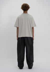 Ανοιχτό γκρι oversized μπλουζάκι κοντό μανίκι, με στρογγυλή λαιμόκοψη, συνδυασμένο με μαύρο παντελόνι φαρδύ που διαθέτει υφή.