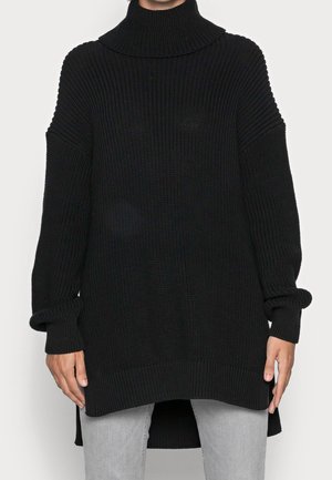 Pull en tricot noir surdimensionné avec col haut, texture côtelée, manches longues et fentes sur les côtés à l'ourlet. Matériau doux, design décontracté.