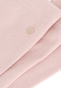 Un tessuto lavorato a maglia di colore rosa chiaro con una texture morbida, caratterizzato da un logo sottile in filo dorato. Include cuciture lungo i bordi.