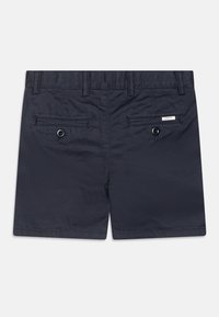Mörkblå shorts i slät tyg, med två bakfickor med knappstängning och en liten logotyp på den högra fickan.