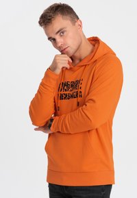 Felpa arancione con grafica nera, dotata di tasca a canguro, cappuccio con cordino e polsini a costine. Tessuto liscio; vestibilità casual.