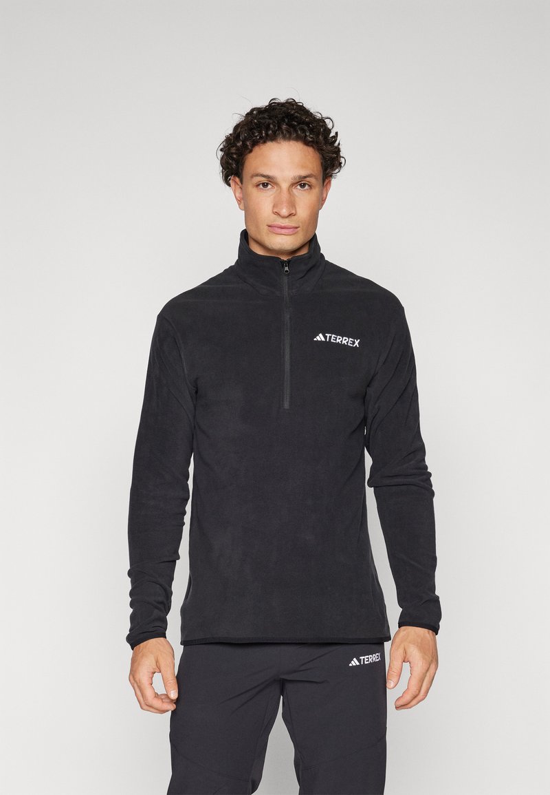Svart fleece genser med halv-glidelås og lange ermer. Har et TERREX-logo på brystet, glatt tekstur og tettsittende design.