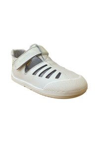 Zapato de cuero blanco con diseño calado, correa de Velcro y suela de goma texturizada. Presenta una punta redonda y una estructura transpirable.