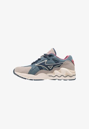 Sneaker da uomo in denim blu con dettagli in suede grigio, dotate di una suola intermedia bianca ondulata e un tallone rosa, progettate per comfort e stile.