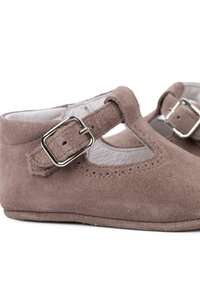 Chaussures Mary Jane en daim marron avec un bout rond, une boucle sur le côté et un design découpé ; texture douce et construction légère.