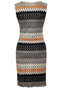 Stickad klänning med en figurnära silhuett. Har ett zigzagmönster i svart, gräddfärgad och orange toner. Ärmlös design. Scallopad fåll.