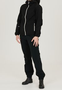 Black waterproof jacket with a high collar and front zip, paired with black windbreaker pants. Both have elastic cuffs and pockets.