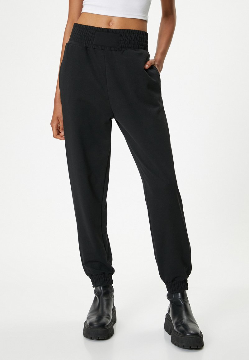 Zwarte joggingsbroek met een smocktailleband, zijzakken en elastische boorden, gemaakt van een zachte stof die geschikt is voor casual gebruik.