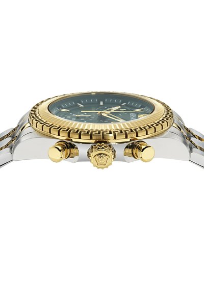 To-tone armbåndsur med grøn skive, guld bezel med teksturerede detaljer og en rustfrit stål rem med logo-detalje på kronen.