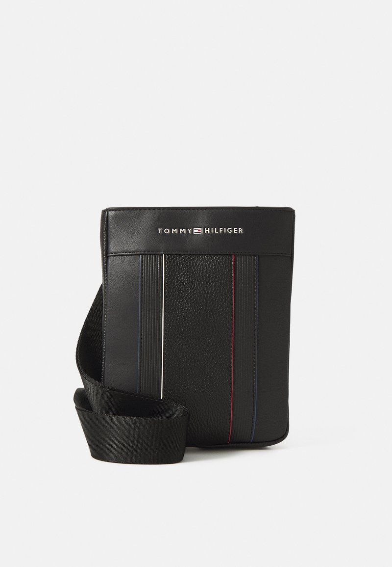 Svart lær crossbody-veske med teksturert overflate, med vertikale striper i rødt, hvitt og blått, samt en skulderrem. Logoen vises foran.