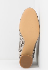 Semelle de chaussure avec dessous en caoutchouc marron clair et talon rond texturé, dessus imprimé serpent dans les tons de beige, taille 37 visible, sur fond blanc.