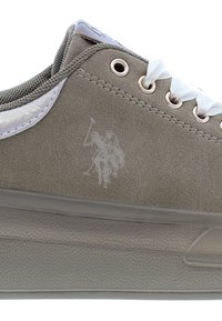 Zamszowe szare sneakersy z białymi sznurówkami, metalowymi oczkami i przezroczystą gumową podeszwą. Posiada delikatne wytłoczone logo na boku.