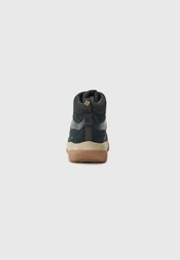 Dark green hiking boot with a sturdy sole, showing texture and height, positioned against a plain white background.