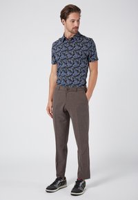 Short-sleeve polo shirt with a blue floral pattern, paired with brown checkered trousers and black sneakers with white soles.