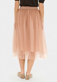 Gonna in tulle plissettato di un rosa tenue, con una vita alta e spessa. La gonna presenta un tessuto trasparente a strati con una texture leggera e ariosa.
