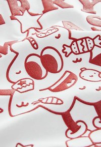 Rot-weißer Stoff mit Mustern, die cartoonartige Charaktere, Süßigkeiten und Sterne zeigen. Das Design hat ein weiches, strukturiertes Aussehen.