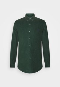 Zelená kordurová košile na knoflíky s dlouhými rukávy, límečkem, předními knoflíky a malým purpurovým logem na hrudi. Texturovaná látka.