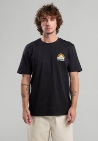 T-shirt in cotone nero con maniche corte. Presenta una piccola grafica di un sole giallo e la scritta "PACE MENTALE" sul lato sinistro del petto. Tessuto morbido.