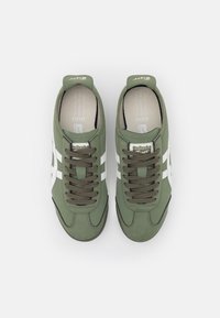 Zapatillas bajas verdes de textil con franjas laterales blancas, cordones marrones y plantilla acolchada, con punta redondeada y suela de goma.