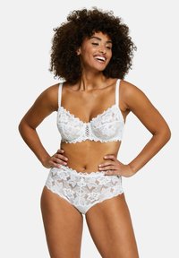 Set di lingerie bianco in pizzo, composto da un bralette con una sezione centrale decorativa e culotte alte a vita con bordi ondulati e motivi floreali.