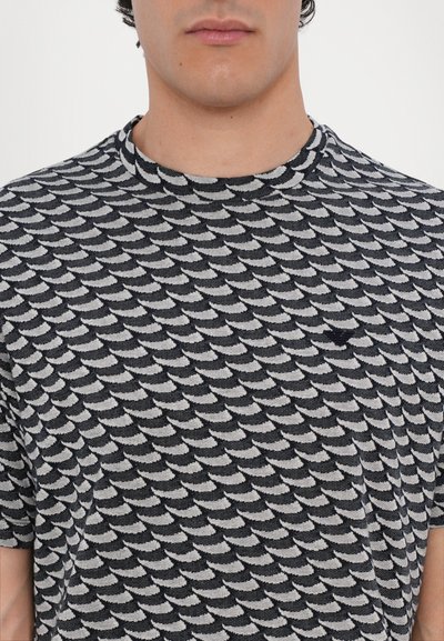 Short-sleeve t-shirt made of knit fabric, featuring a black and white wave pattern, round neckline, and a small logo accent on the chest.